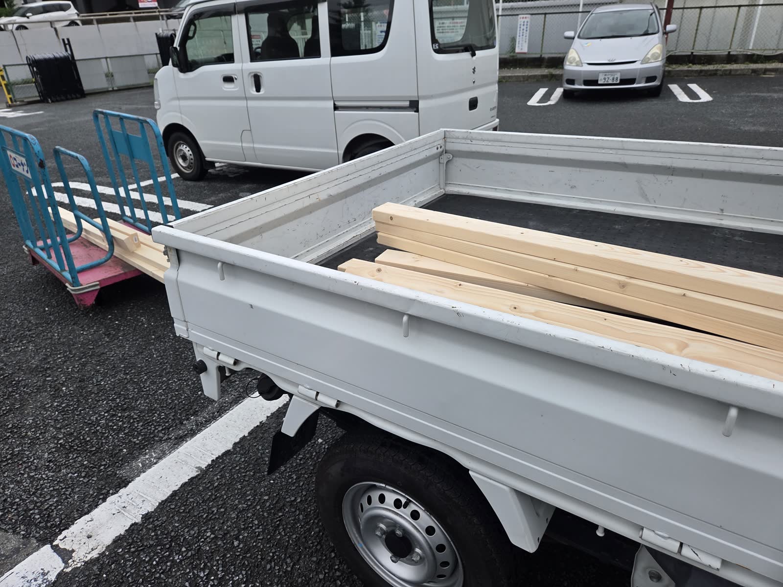 軽トラの荷台に2×4材が積み込まれている。